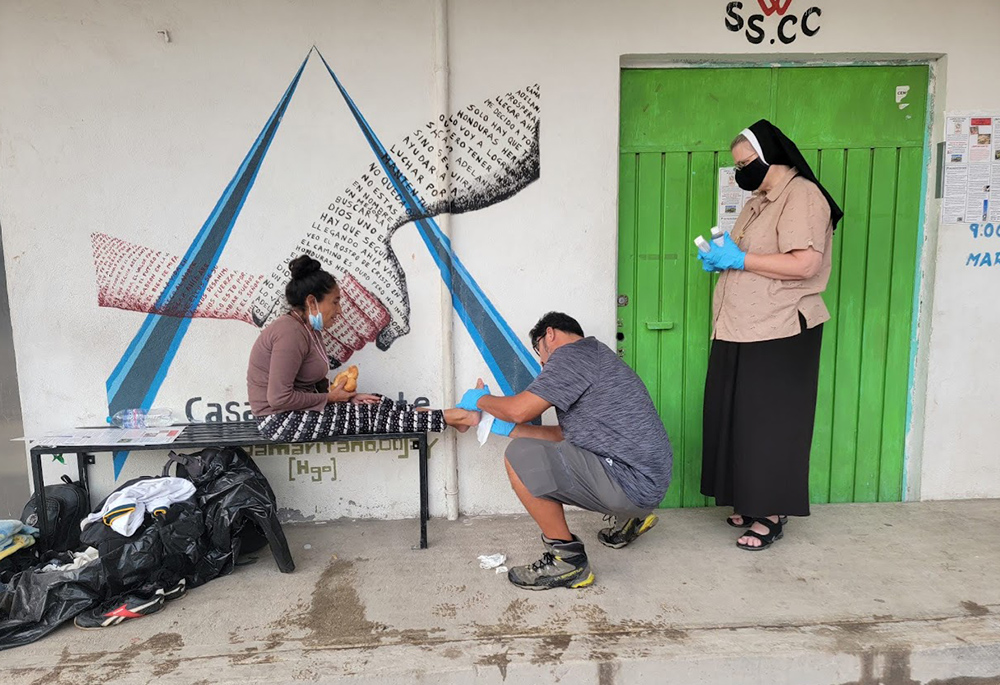 Aguilas volunteer Maurizio Vitela, with Sr. Marie Louise Edwards' assistance, helps clean a migrant's blisters. (Courtesy of Aguilas del Desierto)