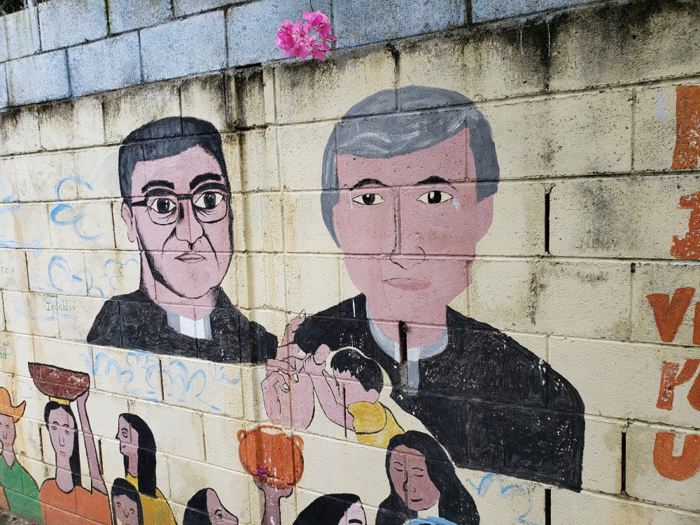 A mural on a wall outside a youth center in Apopa, El Salvador, depicts Archbishop Óscar Romero, left, and Jesuit Fr. Rutilio Grande. The youth center is part of a project of sisters and others called the Color Movement. (GSR / Chris Herlinger)