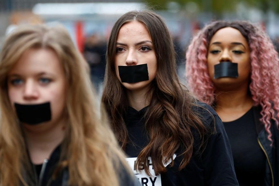 Young women with mouths taped shut protest human trafficking.