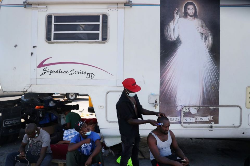 Haitian migrants trying to reach the United States watch another Haitian get a haircut outside a shelter after arriving in Monterrey, Mexico, on Sept. 24. (CNS/Reuters/Edgard Garrido)