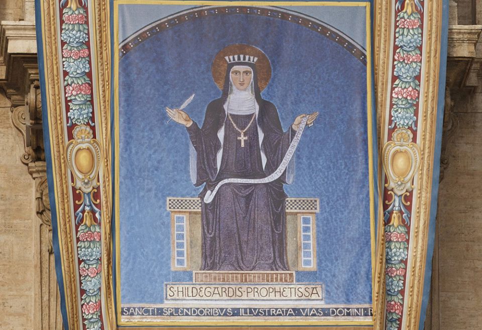 A tapestry showing 12th-century German abbess St. Hildegard of Bingen hangs from the facade of St. Peter's Basilica prior to the opening Mass of the Synod of Bishops for the new evangelization in St. Peter's Square Oct. 7, 2012, at the Vatican. (CNS) A tapestry showing 12th-century German abbess St. Hildegard of Bingen hangs from the facade of St. Peter's Basilica prior to the opening Mass of the Synod of Bishops for the new evangelization in St. Peter's Square Oct. 7, 2012, at the Vatican. (CNS)