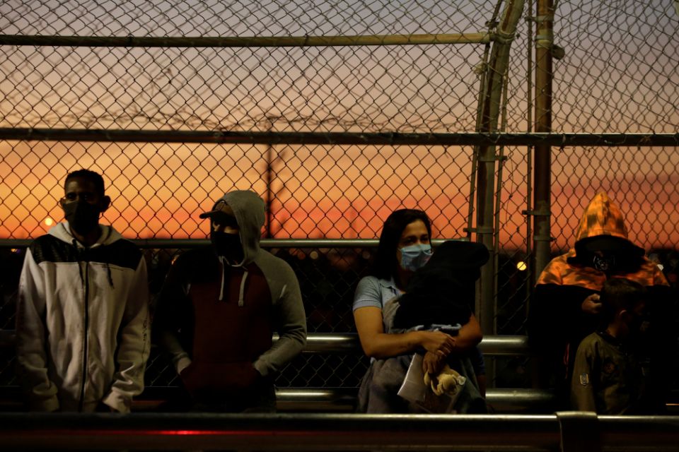 Migrants in the "Remain in Mexico" program line up at the Paso del Norte Mexico-U.S. border bridge in Ciudad Juarez, Mexico, April 21 to reschedule their United States immigration hearings during the coronavirus pandemic. (CNS/Reuters/Jose Luis Gonzalez)