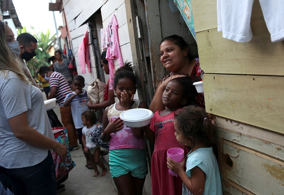 Residents in a poor section of Rio de Janeiro receive food and bread produced at the Sanctuary of Our Lady of Fatima during the COVID-19 pandemic. Volunteers delivered the bread June 24, 2021. (CNS/Reuters/Ricardo Moraes)