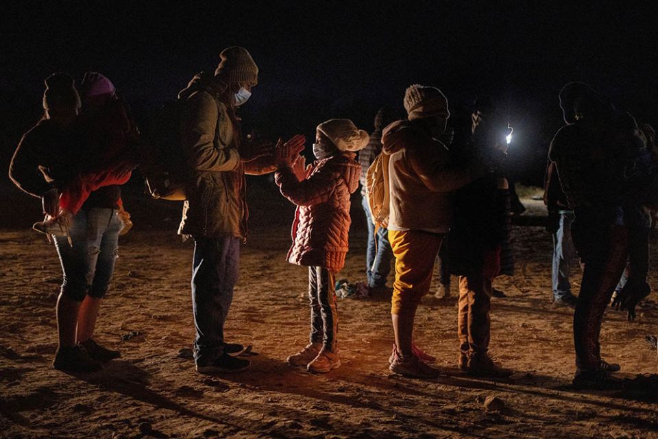 Romando, a migrant from Peru seeking asylum in the United States, plays a hand-clapping game with his daughter Alexa, 7, as they stand in line waiting to be processed in Roma, Texas, Feb. 28. (CNS/Reuters/Adrees Latif)