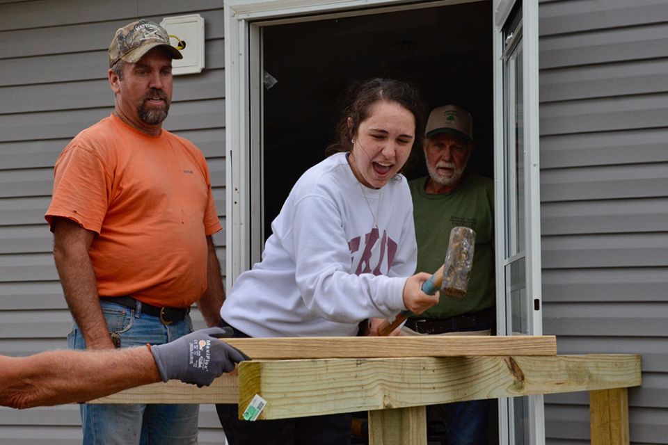 Volunteers Ronnie Mattingly, left, and Jude Leake watch as Lizzi Seyle, also a volunteer, tries the sledgehammer May 23 as the Sisters of Charity of Nazareth's disaster recovery team finishes building a porch on a home badly damaged by a Dec. 10 tornado.