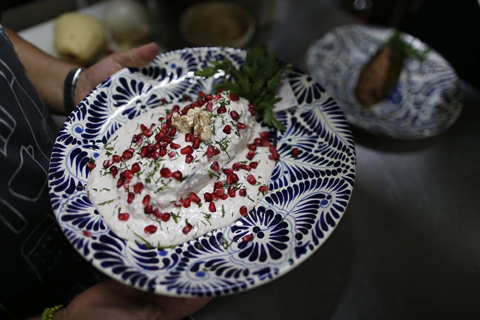 A cook carries out a plate of chiles en nogada to be served to diners at Testal restaurant in downtown Mexico City in September 2019. The recipe was invented in 1821 by a nun whose name has been lost to history. (AP Photo/Rebecca Blackwell, File)