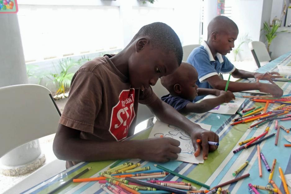 Children draw with crayons in a church-run shelter.