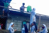 Catholic sisters in the Philippines hand bags of food over a fence to day laborers