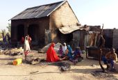 A family is pictured sitting near a damaged home after an attack by suspected members of the Islamist Boko Haram insurgency, Nov. 1, 2018, in Bulabulin, Nigeria. (CNS/Reuters/Kolawole Adewale)