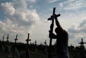 A volunteer places a cross with a number on a grave of an unidentified person during an Aug. 17 mass burial ceremony in Bucha, Ukraine, as Russia's attack on Ukraine continues. (CNS/Reuters/Valentyn Ogirenko)